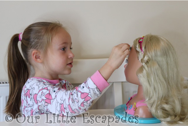 little e applying cat make-up baby born sister styling head