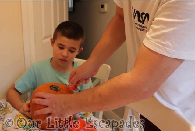 ethan watching darren carving pumpkins