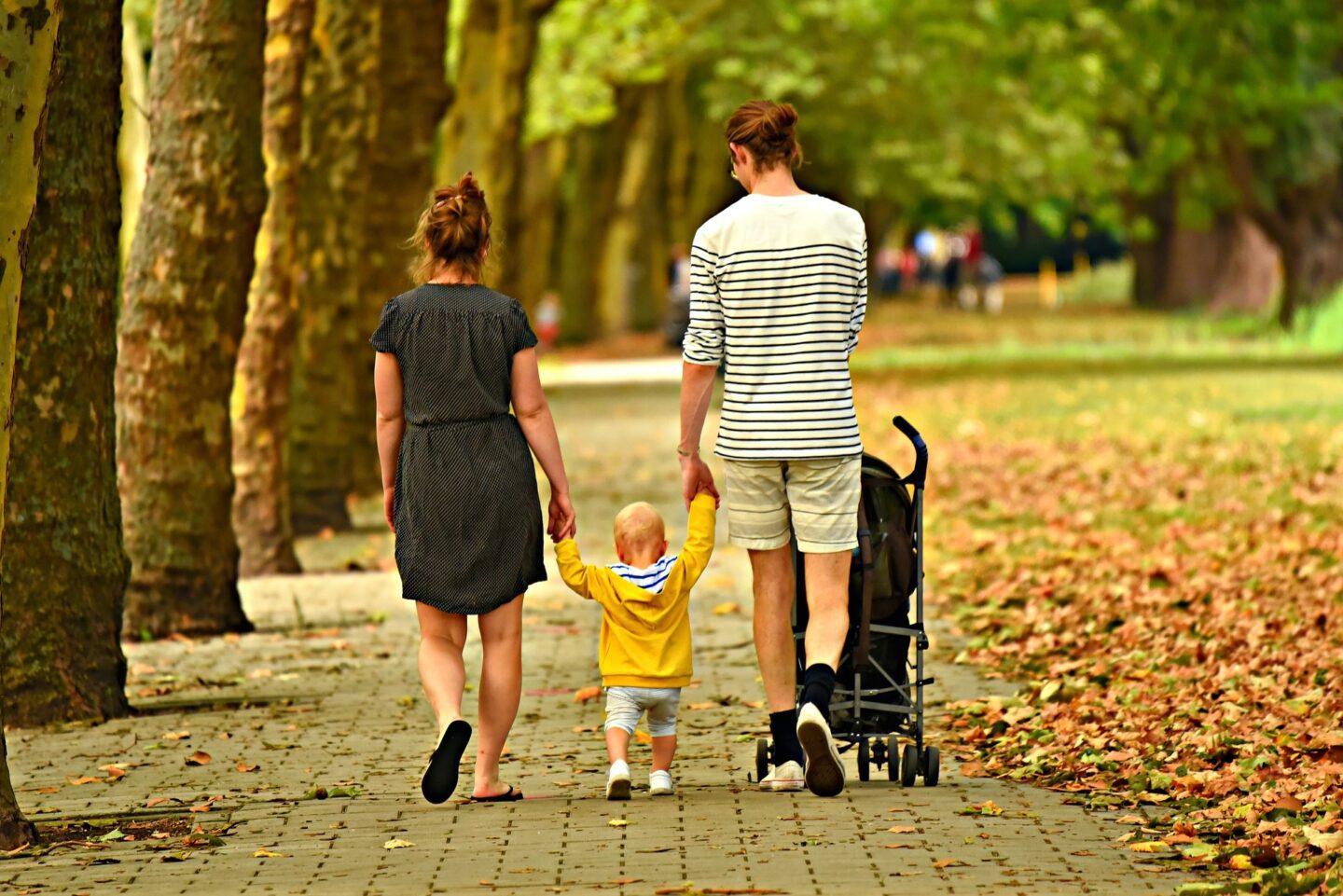 walking family holding toddlers hands street