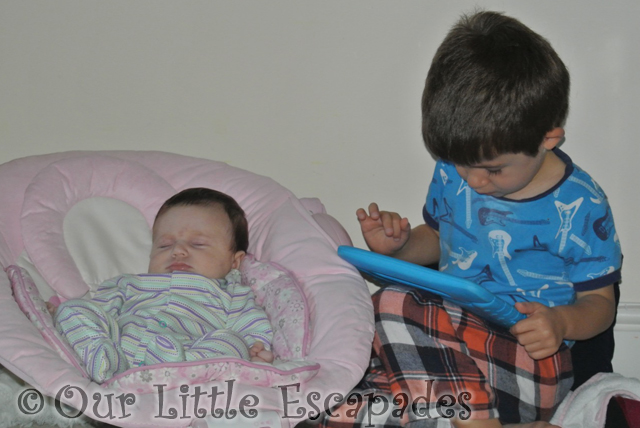 little e asleep baby bouncer ethan beside playing ipad