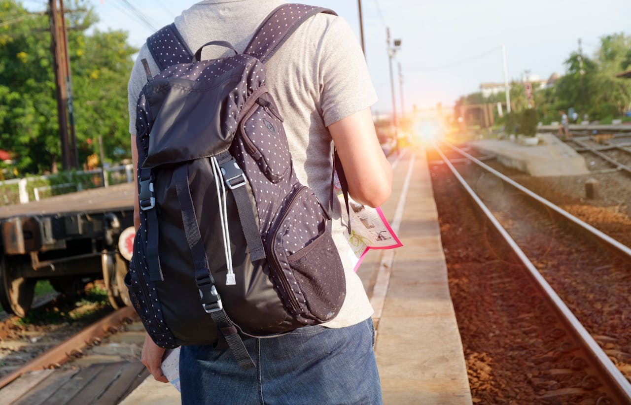 person in grey top with backpack waiting for train