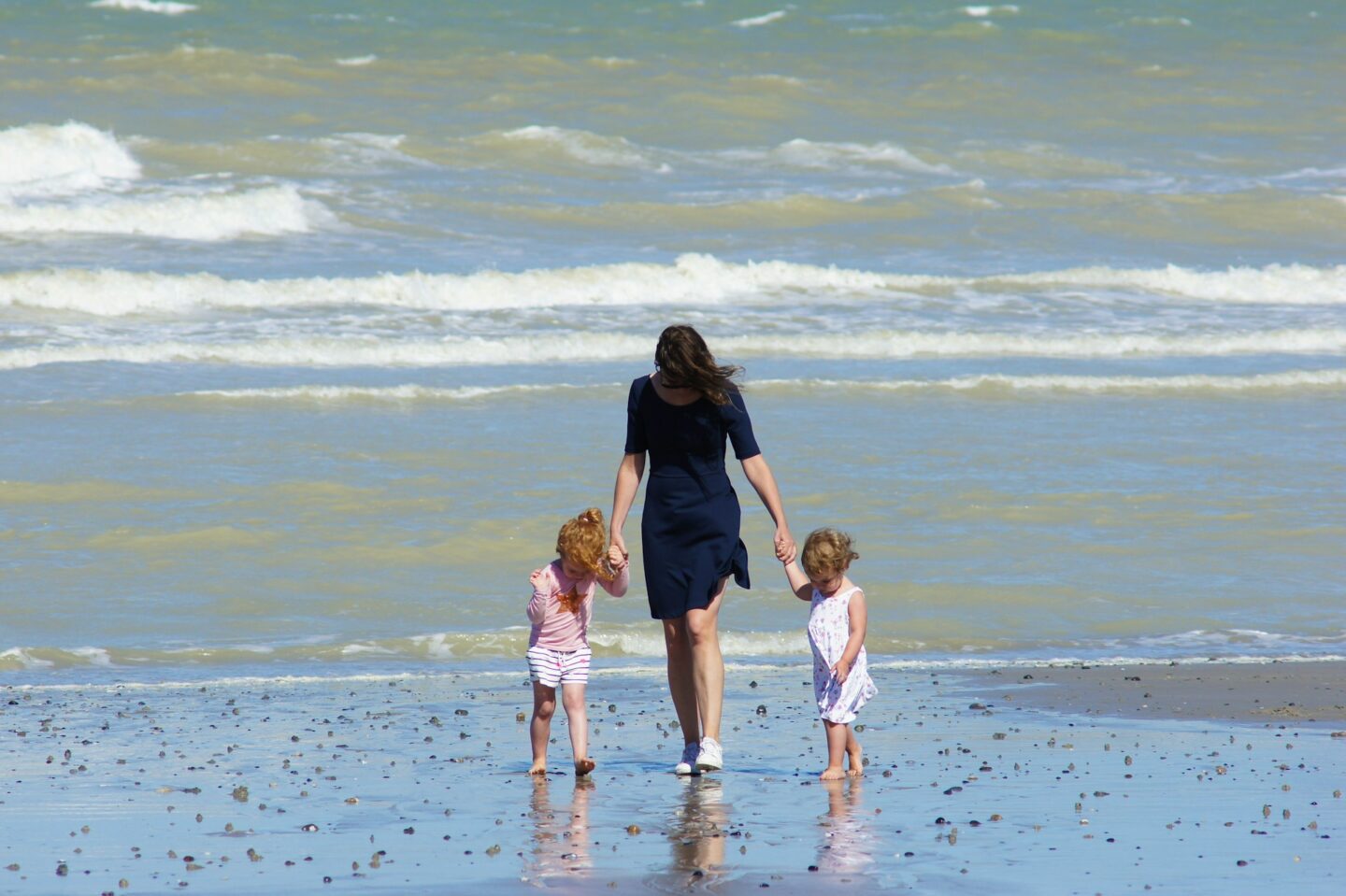 woman with 2 children walking on beach travel