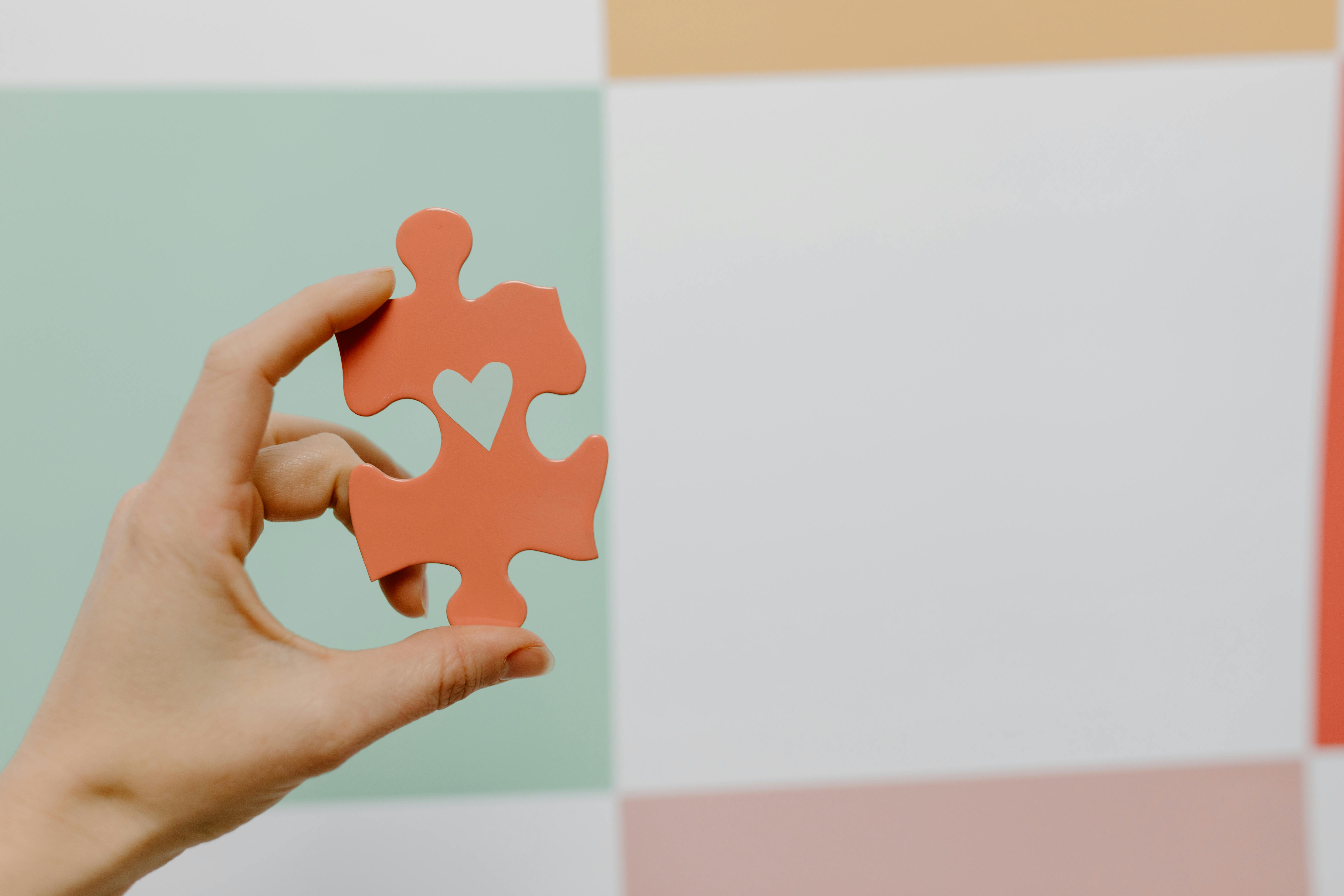 close up of person holding a puzzle piece with a heart separation